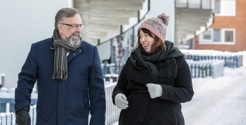 Två personer går ut och går i snöigt bostadsområde