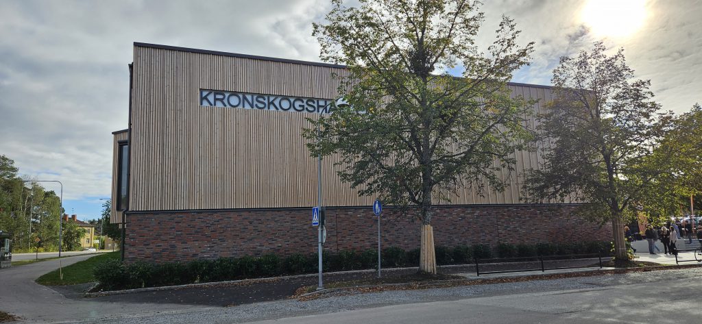 Exteriör Kronskogshallen, idrottshall med fasad av trä och tegel.