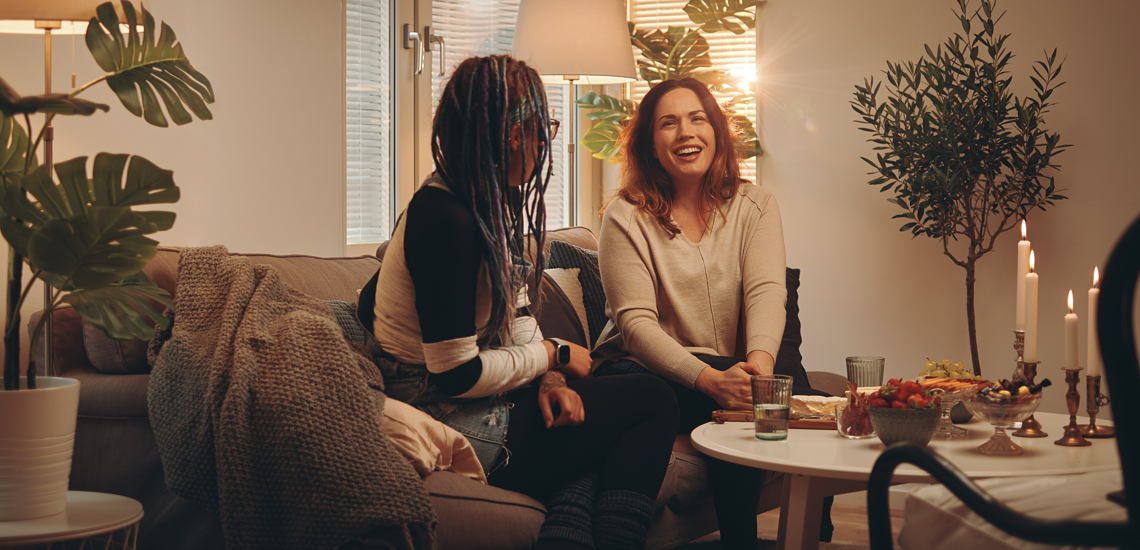 Två personer sitter i soffan och har det trevligt med tända ljus och god mat